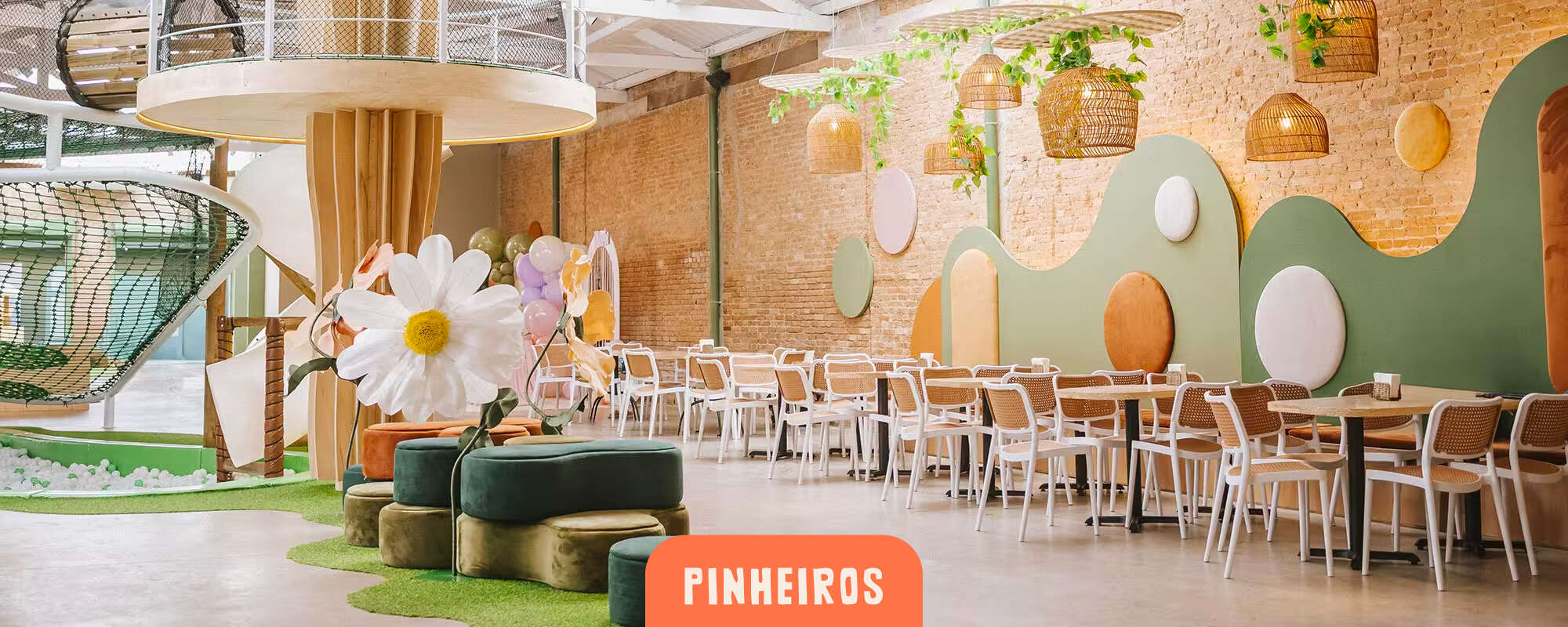 Cachola Pinheiros - salão interno com decoração de flor gigante, poltronas de veludo e área de mesas com parede de tijolinho aparente