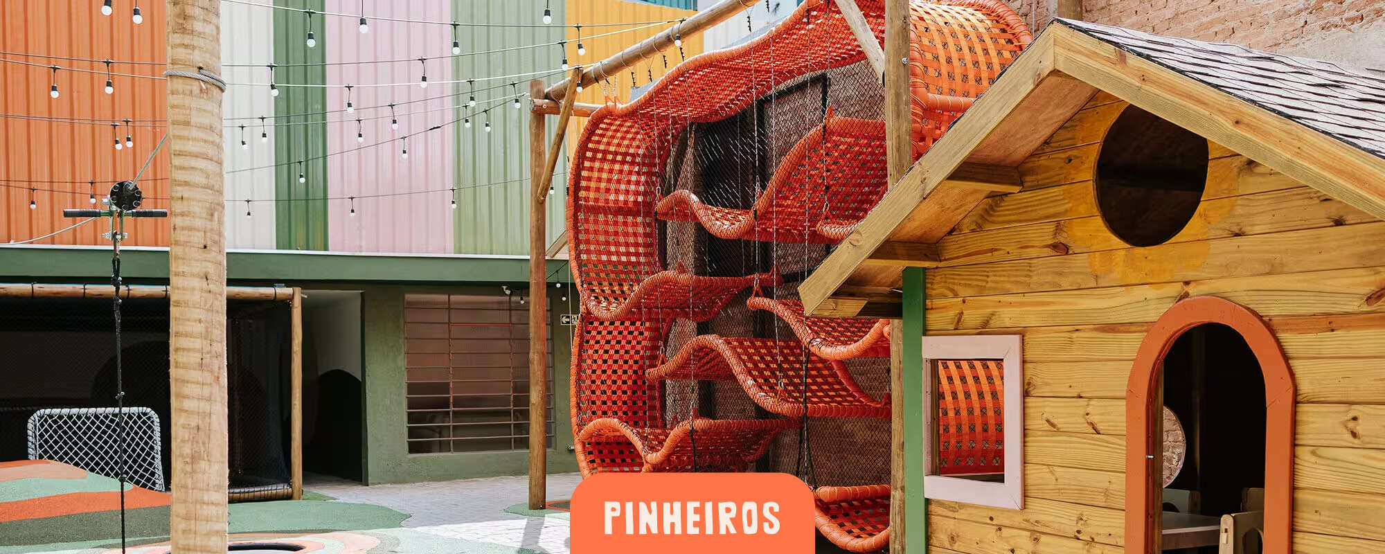 Cachola Pinheiros - pátio externo com casinha de madeira, estrutura de rede laranja e trampolins no piso